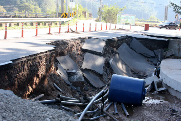 7일 오후 경북 영덕군 축산면 염장삼거리 인근 도로가 일부 무너져 차가 아슬아슬하게 다니고 있다. 이 도로는 6일 한반도를 지나간 태풍 ‘콩레이’ 영향으로 많은 비가 내리면서 붕괴했다. 2018.10.7  연합뉴스