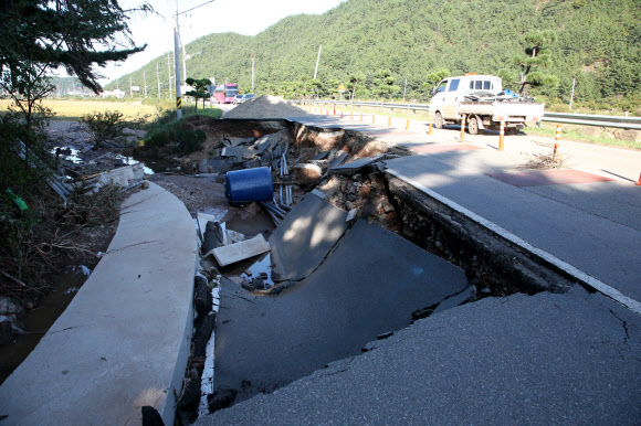 7일 오후 경북 영덕군 축산면 염장삼거리 인근 도로가 일부 무너져 차가 아슬아슬하게 다니고 있다. 이 도로는 6일 한반도를 지나간 태풍 ‘콩레이’ 영향으로 많은 비가 내리면서 붕괴했다. 2018.10.7  연합뉴스