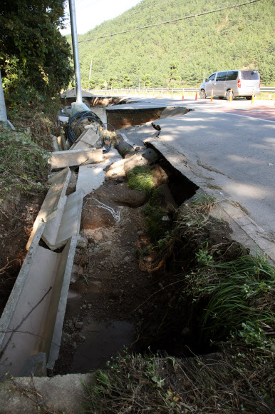 7일 오후 경북 영덕군 축산면 염장삼거리 인근 도로가 일부 무너져 차가 아슬아슬하게 다니고 있다. 이 도로는 6일 한반도를 지나간 태풍 ‘콩레이’ 영향으로 많은 비가 내리면서 붕괴했다. 2018.10.7  연합뉴스