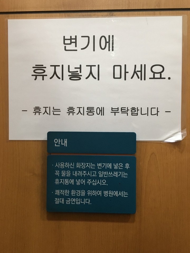 지난 9일 서울의 한 대형 병원 화장실에 써붙여진 안내문. A4 용지에는 “변기에 휴지넣지 마세요”라고 써있고, 바로 아래 안내문에는 “사용하신 화장지는 변기에 넣은 후 꼭 물을 내려달라”고 적혀 있다. 독자 제공