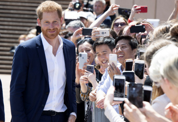 영국의 해리 왕자가 16일(현지시간) 호주 시드니 오페라 하우스 앞에 모인 시민들에게 인사를 하고 있다. 해리 왕자와 부인 메건 마클은 16일간 호주와 남태평양의 영연방 국가들을 방문한다. AP 연합뉴스