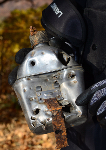 25일 오전 강원도 철원군 철원읍 백마고지 인근 화살머리고지에서 국방부 유해발굴감식단원이 함께 발굴된  6.25  전투 당시 전투 사용되던, 총알 구멍이 숭숭 뚫린 수통을 보여주고 있다. 2018. 10. 25 사진공동취재단