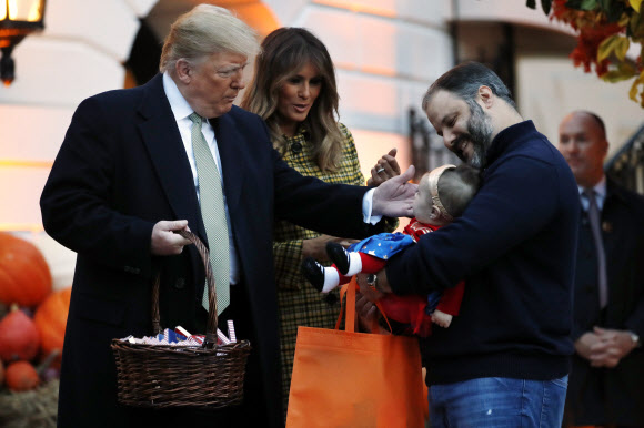 도널드 트럼프 미국 대통령 부부가 28일(현지시간) 미국 워싱턴 D.C. 백악관에서 핼러윈데이 행사를 열고 어린이들에게 초콜릿과 캔디 등을 나눠주며 즐거운 시간을 보내고 있다. AP 연합뉴스