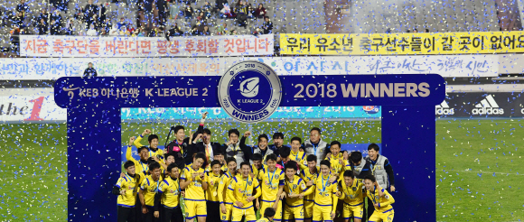 우승 트로피를 들어올린 아산 무궁화 프로축구단 뒤로 해체를 반대하는 플래카드가 걸려 있다.     2018. 11. 5 정연호 기자 tpgod@seoul.co.kr