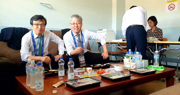 파푸아뉴기니 프레스센터. 컵라면으로 식사를 때우는 김현철 경제보좌관과 김의겸 대변인. 브리핑 작성에 열중하는 고민정 부대변인의 모습도 보인다.  청와대 제공