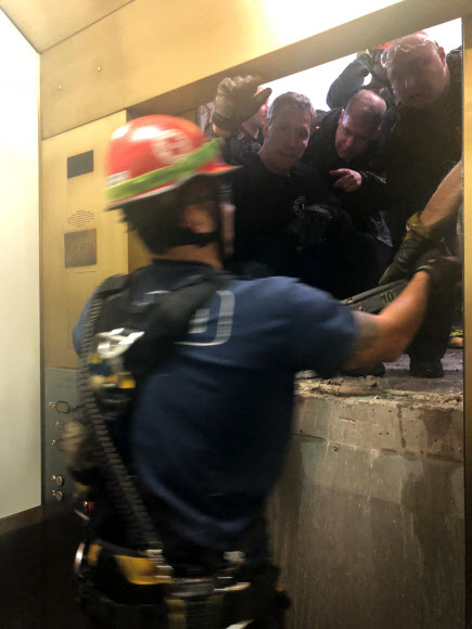 미국 소방대원이 지난 16일(현지시간) 시카고 존 핸콕 센터 건물 95층에서 11층까지 추락하다 멈춘 엘리베이터의 문을 열고 엘리베이터 안에 갖힌 탑승객들을 구조하고 있다.  시카고 로이터 연합뉴스