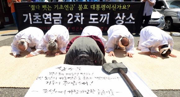 한 시민단체 회원들이 2015년 7월 서울 종로구 청운효자동 주민센터 앞에서 ‘줬다 뺏는 기초연금’ 개선을 요구하는 도끼상소 퍼포먼스를 하고 있다. 손형준 기자 boltagoo@seoul.co.kr