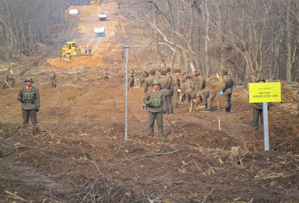 국방부는 22일 남북이 공동유해발굴을 위한 지뢰 제거 작업을 진행하는 강원도 철원 비무장지대(DMZ) 내 화살머리고지에서 전술 도로를 연결했다고 밝혔다. 사진은 도로 연결 작업에 참여한 남북 관계자들이 군사분계선 인근에서 작업하는 모습.  국방부 제공