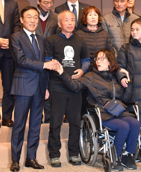 23일 오전 서울 중구 프레스센터에서 열린 삼성전자-반올림 중재판정 이행합의 협약식이 끝난 뒤 기념촬영 때 삼성전자 김기남 대표이사(왼쪽)가 반올림 황상기 대표(왼쪽 두번째)의 중재로 피해자 한혜경씨와 악수하고 있다. 2018.11.23 박지환 기자 popocar@seoul.co.kr