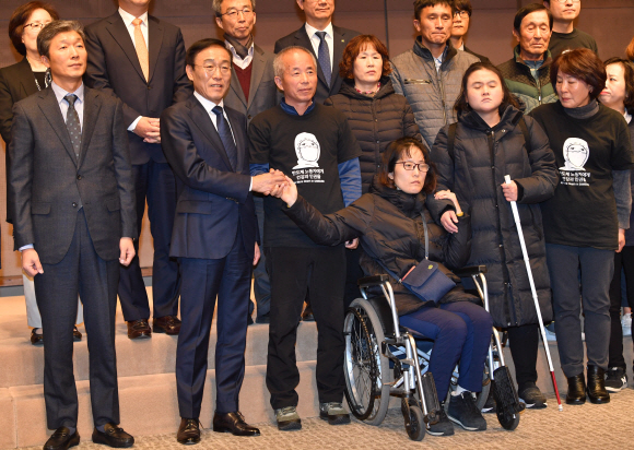 23일 오전 서울 중구 프레스센터에서 열린 삼성전자-반올림 중재판정 이행합의 협약식이 끝난 뒤 기념촬영 때 삼성전자 김기남 대표이사(왼쪽 두번째)가 반올림 황상기 대표(왼쪽 세번째)의 중재로 피해자 한혜경씨와 악수하고 있다. 2018.11.23 박지환기자 popocar@seoul.co.kr