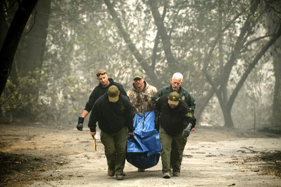 경찰관들이 미국 캘리포니아주 파라다이스에서 대형 산불 ‘캠프 파이어’로 숨진 희생자의 시신을 옮기고 있다. 2018.11.10  AP 연합뉴스