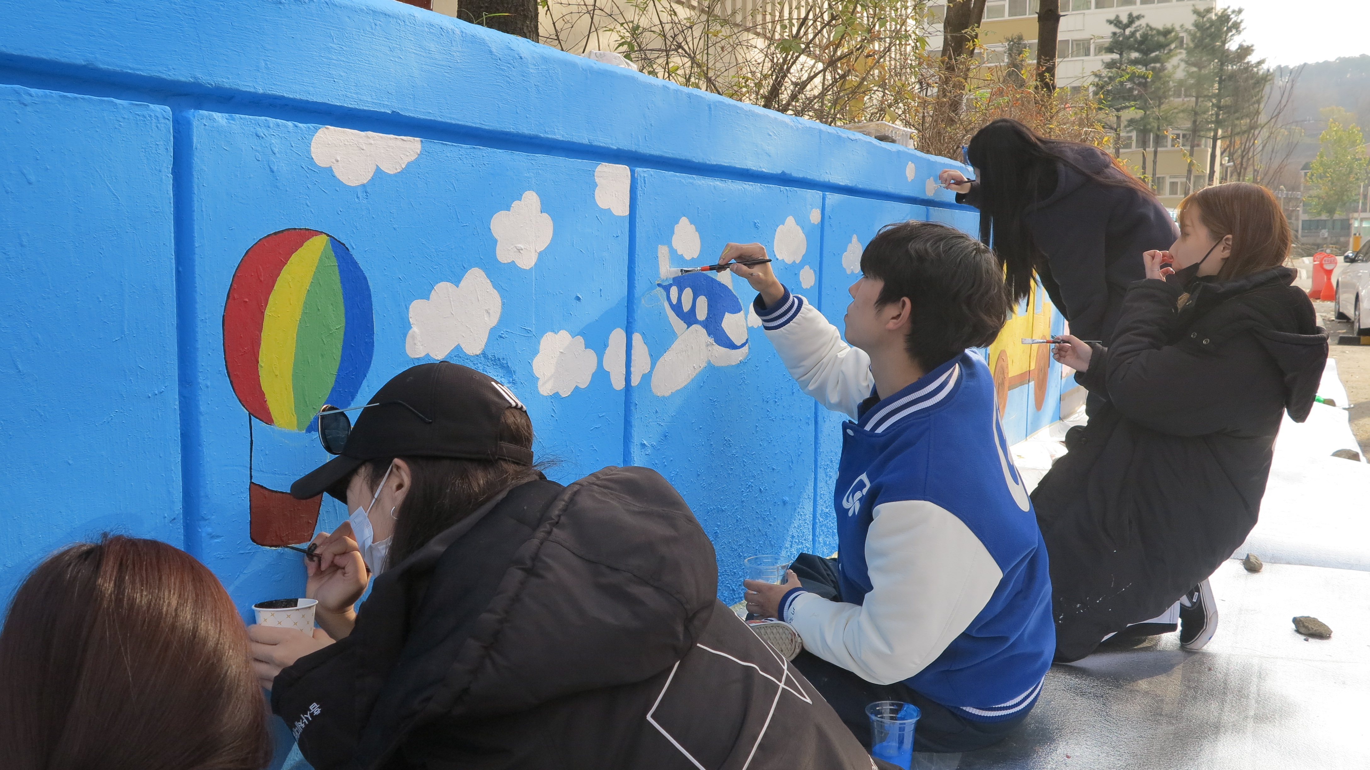 가천대 예술대학 학생들이 25일 성남시에 위치한 임대아파트에서 벽화를 그리며 재능나눔 봉사활동을 펼치고 있다. (가천대 제공) 