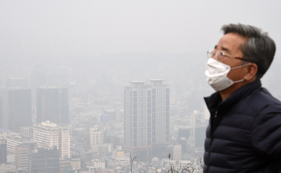 전국적으로 초미세먼지(PM2.5) 수준이 ‘나쁨’ 상태를 보인 가운데 미세먼지(PM10)에 해당하는 중국발 황사까지 겹친 27일 마스크를 쓴 채 서울 중구 남산을 산책하는 한 시민 뒤로 내려다보이는 도심이 뿌옇다. 최해국 선임기자 seaworld@seoul.co.kr