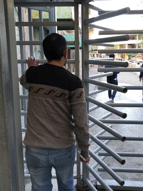 한 팔레스타인 청년이 지난 19일 팔레스타인 자치지역 서안지구 헤브론 내 이스라엘 정착촌 출입구에 설치한 철제 통행 차단기를 지나가고 있다. 헤브론에 주둔한 이스라엘군은 유사시 이 문을 폐쇄한다.