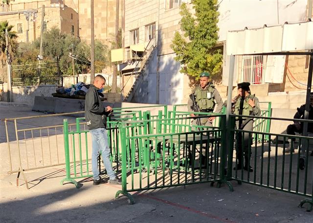 팔레스타인 자치지역 서안지구 헤브론 내 이스라엘 정착촌 입구에서 19일 한 팔레스타인 청년(왼쪽)이 이스라엘 군인에게 자신의 소지품을 꺼내 보여 주고 있다. 이스라엘군은 정착촌 내 유대인 8가구의 안전을 지킨다는 명목으로 헤브론에 주둔 중이다.