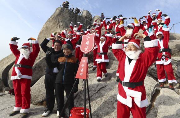 2일 고양 북한산 백운대 정상에서 산타복을 입은 쌩곰등반클럽, 구세군자선냄비본부, 국립공원 관리공단, 코오롱등산학교 관계자들이 구세군 자선냄비 행사 발대식을 하고 있다. 박창용 쌩곰등반클럽회장과 산악회원들은 12월 말까지 매주 토,일 8회에 걸쳐 북한산 일원에서 자선모금 캠페인을 할 계획이다. 2018.12.2 연합뉴스