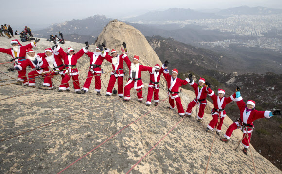 2일 고양 북한산 백운대 정상에서 산타복을 입은 쌩곰등반클럽, 산이좋아 산악회원들이 구세군 자선냄비 행사 발대식을 맞아 포즈를 취하고 있다. 박창용 쌩곰등반클럽회장과 산악회원들은 12월 말까지 매주 토,일 8회에 걸쳐 북한산 일원에서 자선모금 캠페인을 할 계획이다. 2018.12.2  연합뉴스