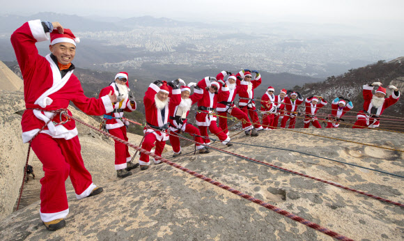 2일 고양 북한산 백운대 정상에서 산타복을 입은 쌩곰등반클럽, 산이좋아 산악회원들이 구세군 자선냄비 행사 발대식을 맞아 포즈를 취하고 있다.  박창용 쌩곰등반클럽회장과 산악회원들은 12월 말까지 매주 토,일 8회에 걸쳐 북한산 일원에서 자선모금 캠페인을 할 계획이다. 2018.12.2  연합뉴스