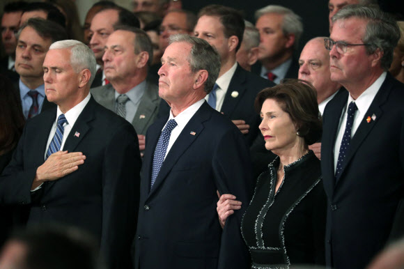 지난달 30일(현지시간) 타계한 조지 H.W. 부시 전 미국 대통령의 시신이 3일 워싱턴DC의 의회 중앙홀에 안치된 가운데 아들인 조지 W. 부시(왼쪽 두 번째) 전 대통령이 추모의식을 지켜보고 있다. AP 연합뉴스