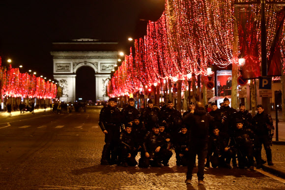 French policemen pose for a photograph on the Champs Elysees following a protest of “yellow vests” (gilets jaunes) against rising costs of living they blame on high taxes in Paris on December 8, 2018. - Paris was on high alert on December 8, 2018 with major security measures in place ahead of fresh “yellow vest” protests which authorities fear could turn violent for a second weekend in a row. 2018.12.09 AFP 연합뉴스