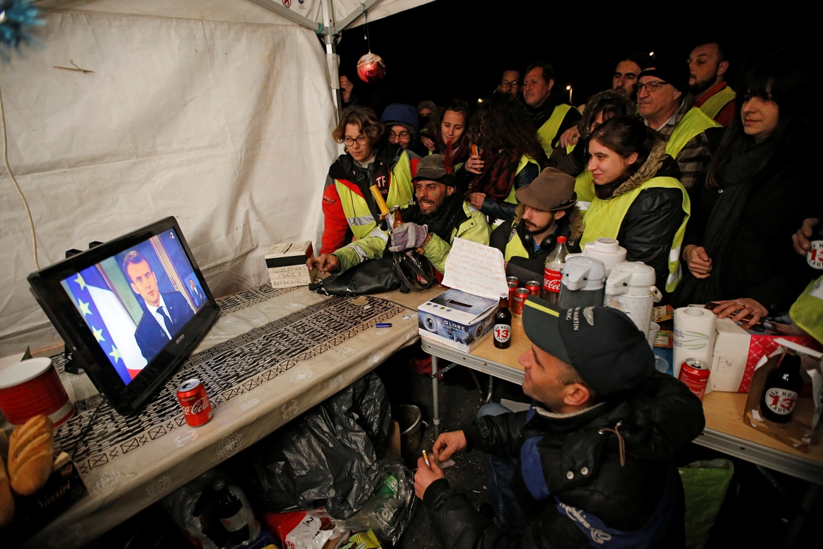 프랑스 ‘노란 조끼’ 집회에 참여한 시민들이 10일(현지시간) 저녁 에마뉘엘 마크롱 대통령의 생방송 연설을 듣고 있다. 로이터 연합뉴스