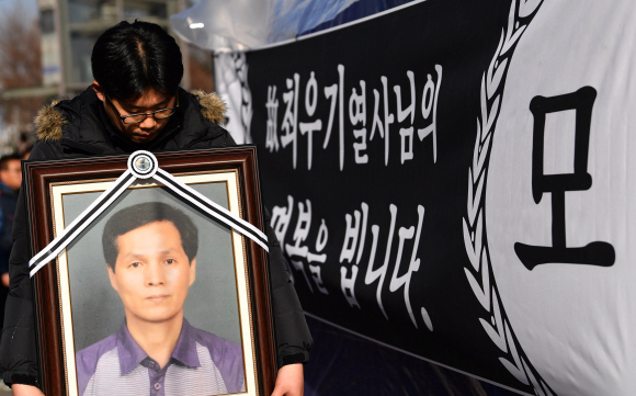 12일 서울 국회앞 국민은행에서 열린 카카오택시 카풀반대 집회에 참석한 택시업계 관계자가 분신자살한 최우기씨의 영정사진을 들고 있다.  2018.12.12 박지환기자 popocar@seoul.co.kr