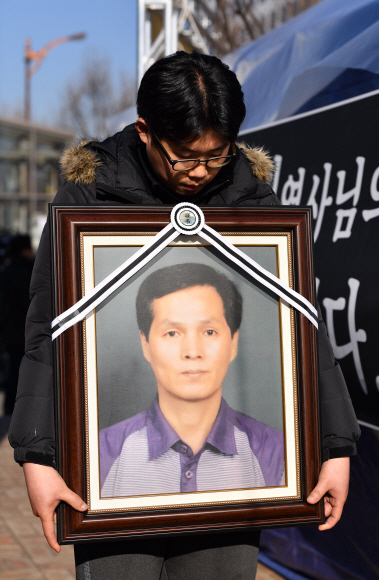 12일 서울 국회앞 국민은행에서 열린 카카오택시 카풀반대 집회에 참석한 택시업계 관계자가 분신자살한 최우기씨의 영정사진을 들고 있다.  2018.12.12 박지환기자 popocar@seoul.co.kr