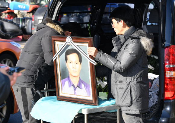 12일 서울 국회앞 국민은행에서 열린 카카오택시 카풀반대 집회에 참석한 택시업계 관계자가 분신자살한 최우기씨의 영정사진을 들고 있다.  2018.12.12 박지환기자 popocar@seoul.co.kr