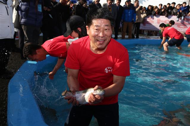 제12회 평창송어축제가 개막한 22일 강원 평창군 진부면 오대천 축제장에서 열린 맨손송어잡기 행사에서 심현정 평창군의원이 송어를 잡아 보이고 있다.2018.12.22 뉴스1