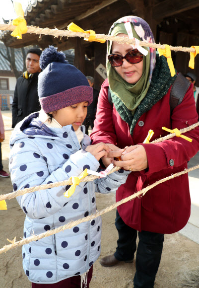 22일 동지를 맞아 열린 서울 남산골한옥마을 세시절기행사 ‘동지첨치’에 참가한 외국인 관광객 가족이 소원을 적어 달고 있다. 2018.12.22  연합뉴스