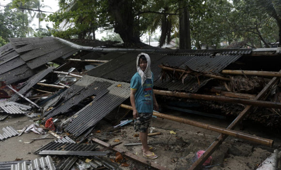 23일(현지시간) 인도네시아 카리타에서 한 남성이 쓰나미로 피해를 입은 자신의 집 앞에 서있다. AP 연합뉴스