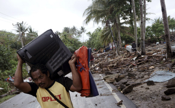 23일(현지시간) 인도네시아 순다해협에서 쓰나미가 발생한 후 피해지역인 반텐 주 안예르 해변에서 주민이 자신의 집에 돌아와 남은 살림살이를 챙기고 있다. EPA 연합뉴스