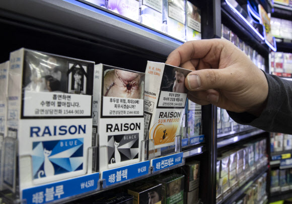 23일 오전 서울 종로구의 한 편의점에서 관계자가 흡연의 위험성을 알리는 경고그림이 변경된 담뱃갑을 들어보이고 있다. 2018.12.23 연합뉴스