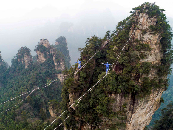 영화 ‘아바타’의 캐릭터로 분장한 두 명의 참가자가 23일(현지시간) 중국 후난 지방의 장가계에서 황시즈하이 산맥의 한가운데를 따라 레이싱하는 경기에서 줄 위를 걸어 건너고 있다. AFP 연합뉴스