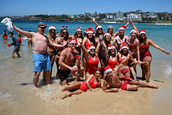 성탄절인 25일(현지시간) 호주 시드니의 본다이 비치를 찾은 여행객들이 산타 모자를 쓰고 즐거운 시간을 보내고 있다. AFP 연합뉴스