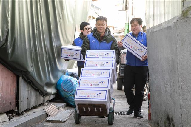 삼성전자 임직원들이 서울 동대문구 쪽방촌을 찾아 거주 어르신들에게 전달할 생필품 세트를 나르고 있다.  삼성전자 제공