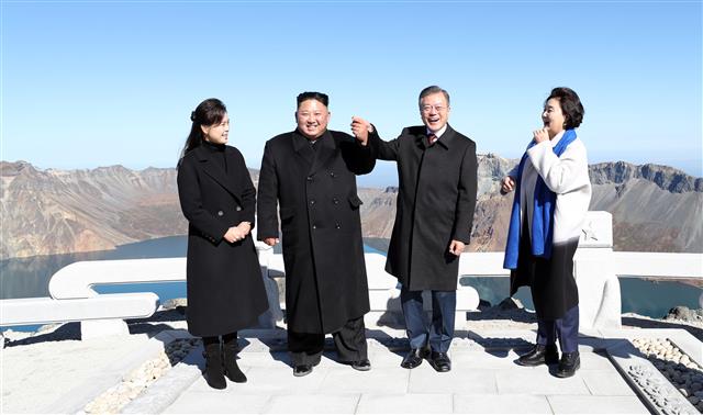 문재인(오른쪽 두 번째) 대통령과 김정은(왼쪽 두 번째) 북한 국무위원장이 지난 9월 20일 백두산 장군봉에서 밝은 표정으로 손을 잡고 있다.  평양사진공동취재단