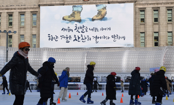첫발  1일 서울 중구 세종대로 서울광장 앞 스케이트장을 찾은 시민들이 스케이트를 즐기는 가운데 서울도서관 외벽의 대형 글판이 새해를 맞아 새 옷을 갈아입고 희망의 메시지를 건네고 있다. 서울시는 지난해 11월 12~26일 진행한 ‘꿈새김판’ 신년 문안 공모전 참가작 895편 중 김경규씨 작품을 당선작으로 추렸다. 김씨는 “이 시린 계절은 때론 천천히 걸어갈 줄 아는 여유를 가져야 한다고 말한다. 새해라고 또 조바심 내며 달려 나갈 게 아니라 마음의 여유를 가지자는 바람으로 창작했다”고 소개했다. <br>도준석 기자 pado@seoul.co.kr