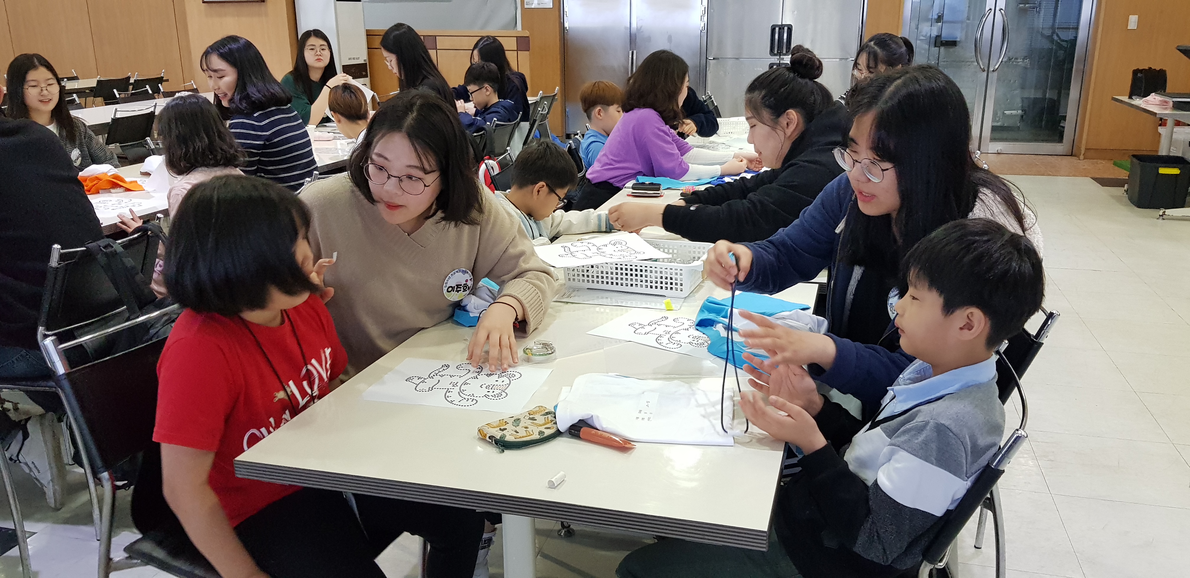 지난해 여름방학에 진행한 서울 금천구의 자원봉사 프로그램에 참여한 청소년들이 지역아동센터 어린이들과 ‘핫픽스 티셔츠 만들기’ 활동을 하고 있다.  금천구 제공 