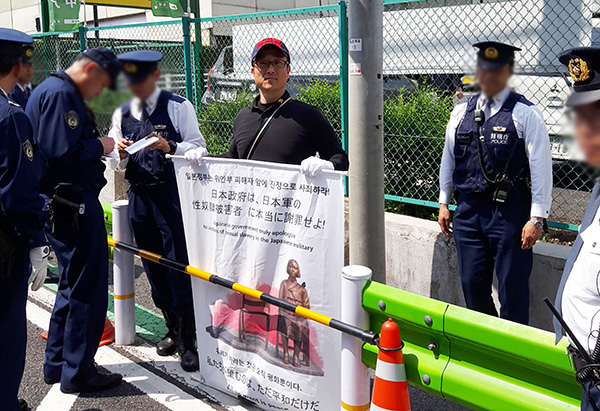 서영근씨가 지난해 4월 12일 주일 한국대사관 앞에서 ‘일본 정부는 위안부 피해자 앞에 진정으로 사죄하라!’고 쓴 피켓을 들고 1인 시위를 하던 중 일본 경찰에 둘러싸여 있다. [사진=서영근씨 제공]