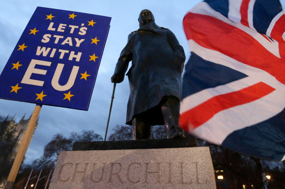 브렉시트에 반대하는 시위대가 15일(현지시간) 영국 런던의 영국 의회 앞에 있는 윈스턴 처칠 동상 앞에서 국기와 플래카드를 들고 항의 집회를 하고 있다. 2019.1.16  신화 연합뉴스 