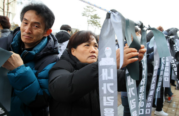 고 김용균 씨의 유가족이 22일 세종시 정부세종청사 산업통상자원부 앞에서 열린 ‘고 김용균 노동자 사회적 타살?죽음의 외주화 주범 산업통상자원부 규탄’ 기자회견에서 ‘내가 김용균이다’ 검은 리본을 묶고 있다.  2019.1.22  연합뉴스