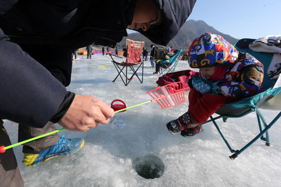 대한민국 ‘원조 겨울축제’인 제19회 인제빙어축제 개막 첫 주말인 27일 부모와 함께 축제장을 찾은 꼬마 강태공이 빙어 얼음낚시를 하고 있다. 인제빙어축제는 내달 3일까지 이어진다. 2019.1.27  연합뉴스