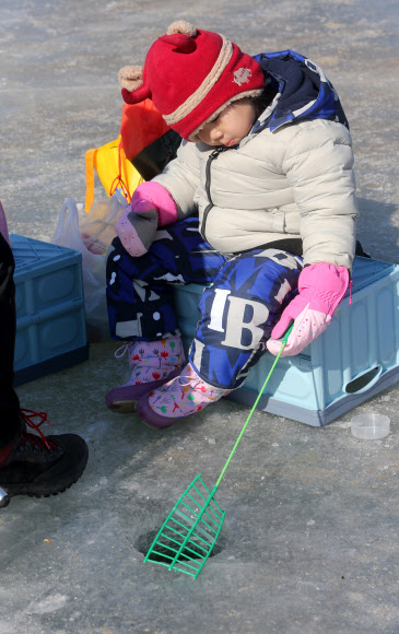 대한민국 ‘원조 겨울축제’인 제19회 인제빙어축제 개막 첫 주말인 27일 부모와 함께 축제장을 찾은 꼬마 강태공이 빙어 얼음낚시를 하고 있다. 인제빙어축제는 내달 3일까지 이어진다. 2019.1.27  연합뉴스