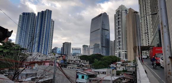 필리핀 수도 마닐라의 ‘강남’으로 떠오른 보니파시오 지역에서 지난 23일 솟아오른 초고층 호화 주택 및 사무용 건물들이 철거를 기다리는 주변 달동네 주택들과 묘한 대조를 이루고 있다. 두테르테 정부의 ‘인프라 우선 정책’이 건설업을 뜨겁게 달구고 있다.