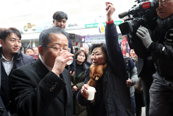 자유한국당 홍준표 전 대표가 8일 오후 경남 창원시 마산합포구 마산어시장을 찾아 상인이 준 소주를 마시는 동안 한 상인이 홍 전 대표를 응원하고 있다. 2019.2.8  연합뉴스