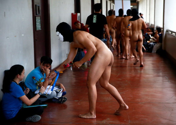 복면을 쓴 사교클럽 회원 남학생들이 8일(현지시간) 필리핀 케손주에 위치한 필리핀 대학교 ‘Oblation Run’ 행사에서 벌거벗은 채 표현의 자유를 외치며 나체 시위를 벌이고 있다. 로이터 연합뉴스