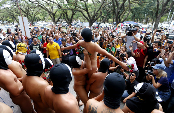 복면을 쓴 사교클럽 회원 남학생들이 8일(현지시간) 필리핀 케손주에 위치한 필리핀 대학교 ‘Oblation Run’ 행사에서 벌거벗은 채 표현의 자유를 외치며 나체 시위를 벌이고 있다. AP 연합뉴스