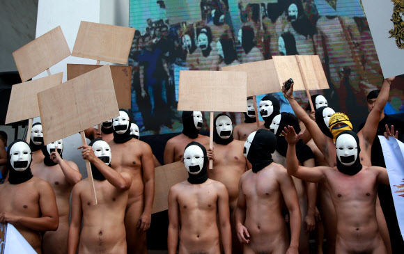 복면을 쓴 사교클럽 회원 남학생들이 8일(현지시간) 필리핀 케손주에 위치한 필리핀 대학교 ‘Oblation Run’ 행사에서 벌거벗은 채 표현의 자유를 외치며 나체 시위를 벌이고 있다. 로이터 연합뉴스