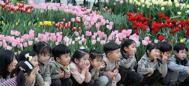 튤립 앞에 앉은 어린이들